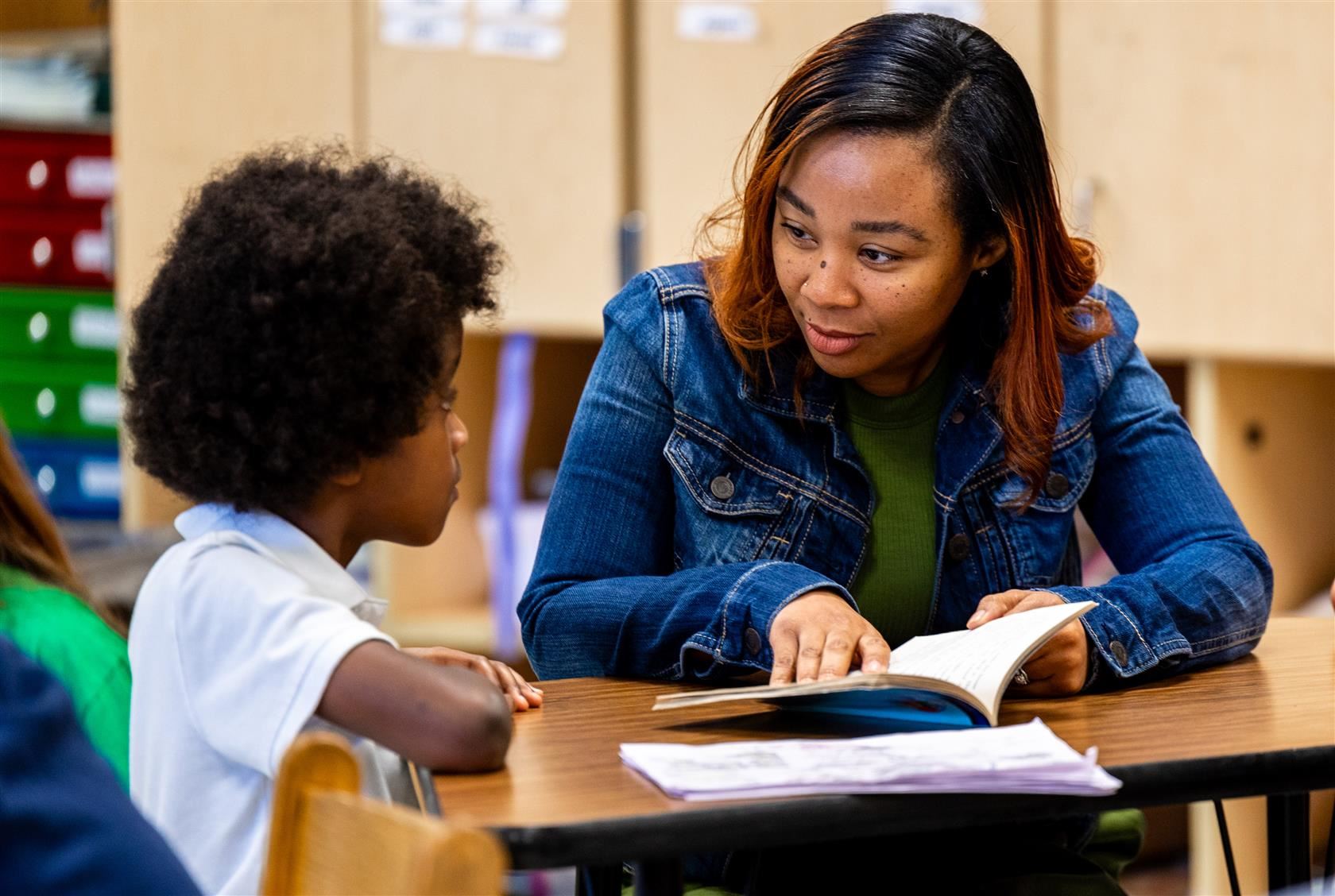 Guardrail 4 - Staffing | Image of CMS staff member reviewing a book with a student
